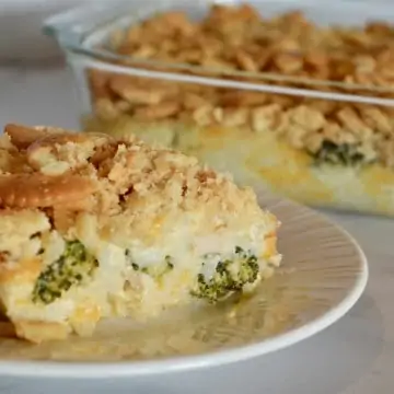 Chicken Rice Broccoli Ritz Casserole on a white plate with serving dish behind it.