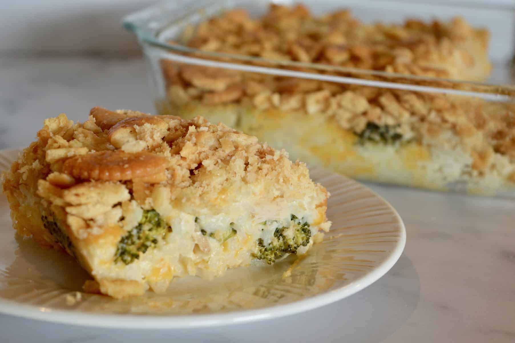 Chicken Rice Broccoli Ritz Casserole on a white plate with serving dish behind it.