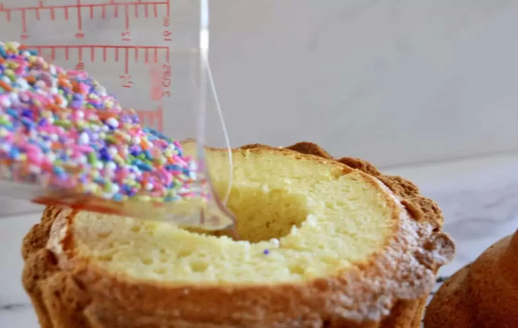 pouring sprinkles into the center of the cake 