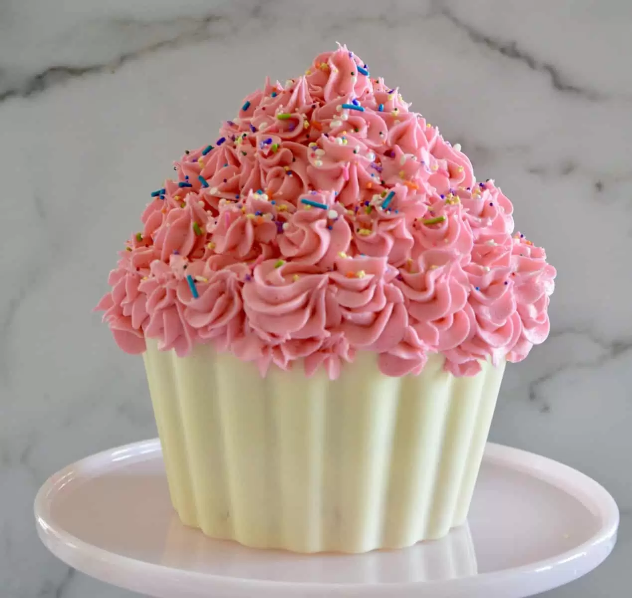 cupcake cake on a pink pedestal with sprinkles