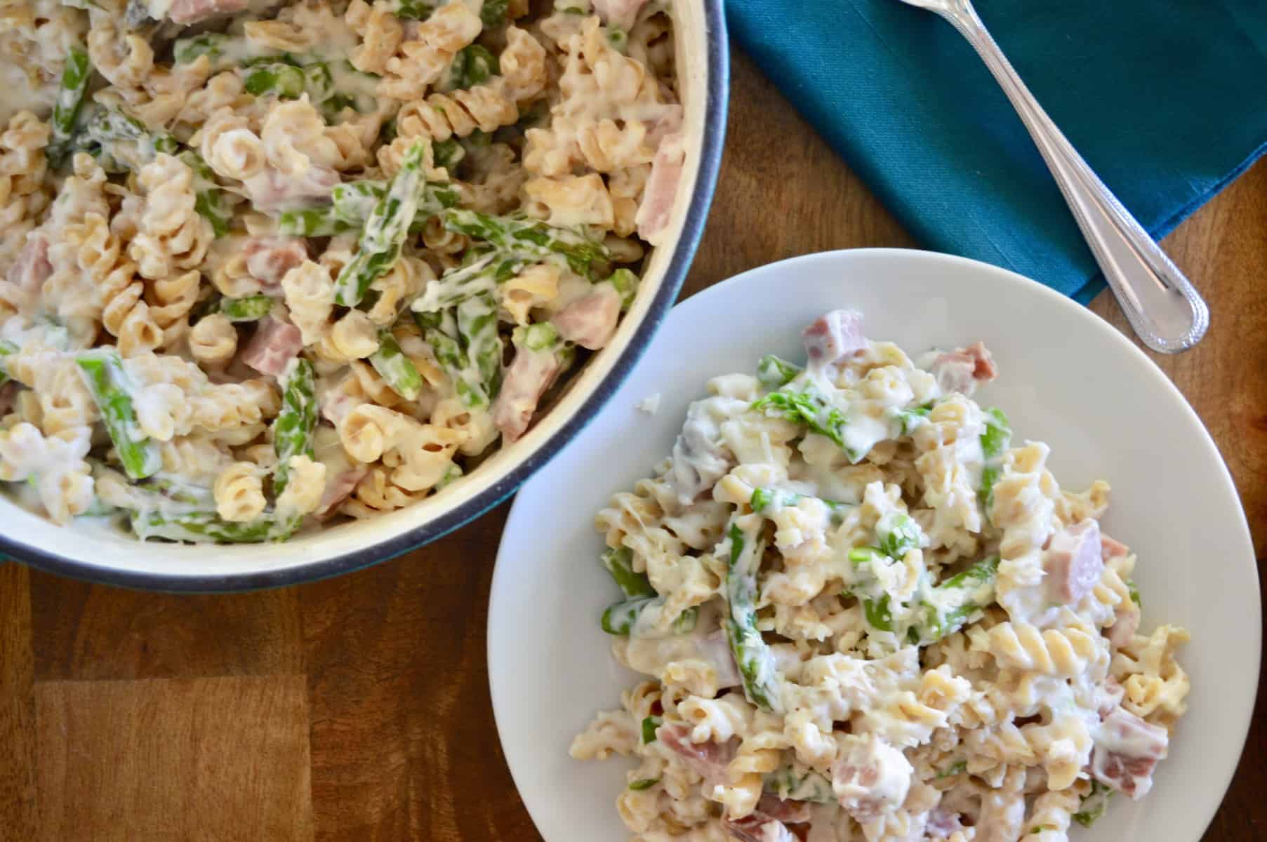 Creamy Ham and Asparagus Pasta in a white plate on a wooden tray