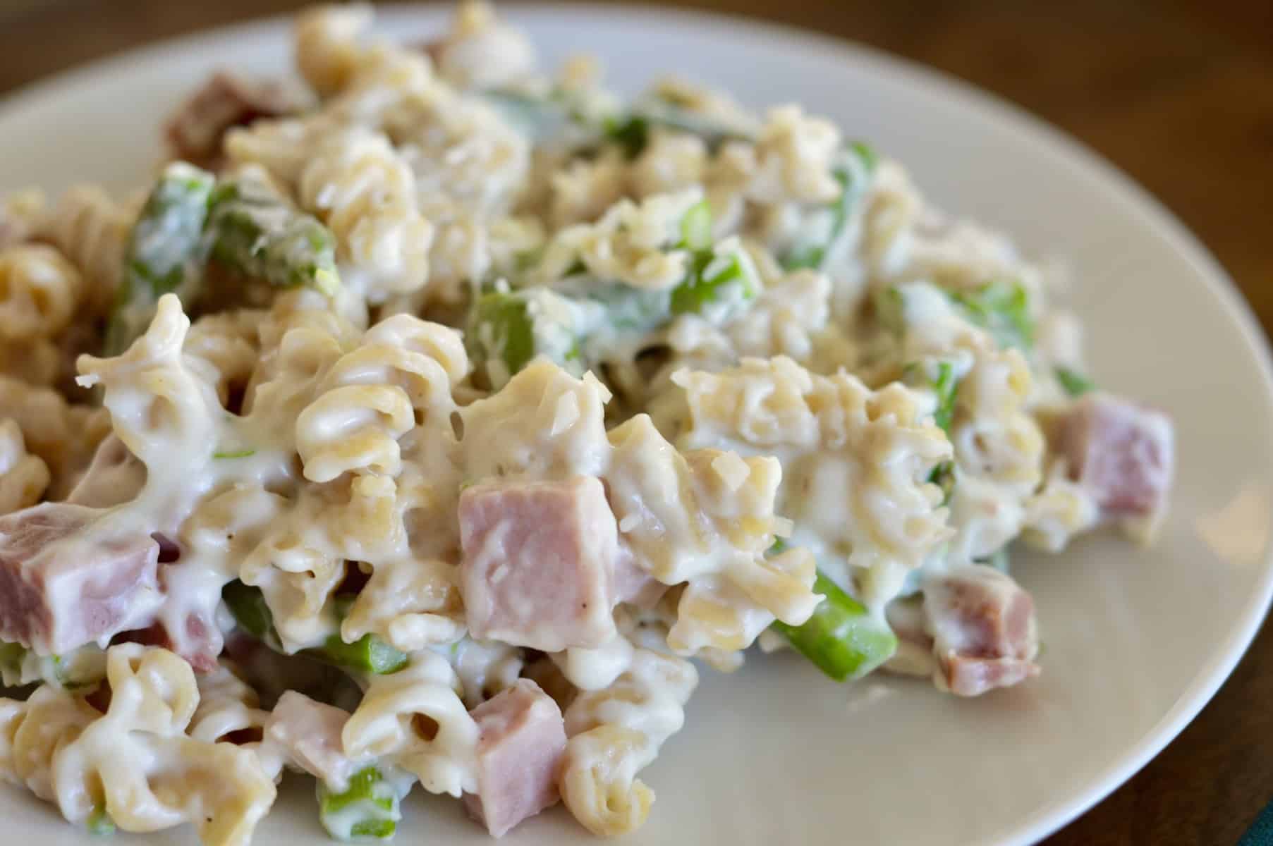 ham and asparagus pasta on a white plate 