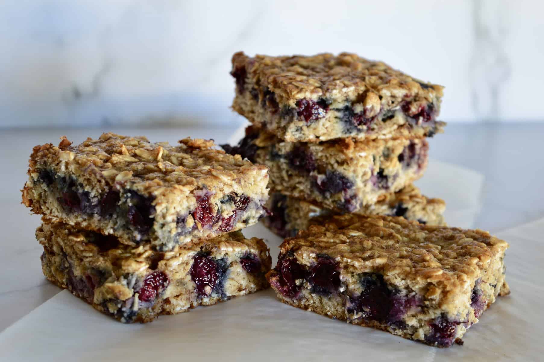 Blueberry Banana Oat Bars stacked on each other on a white background