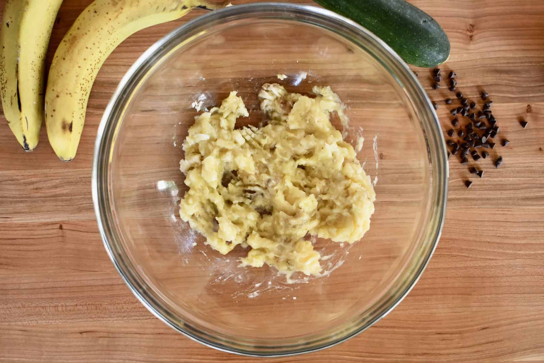 overhead photo of mashed bananas in a glass bowl. 