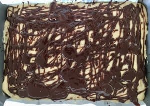Chocolate drizzle over cooled bars in a pan.
