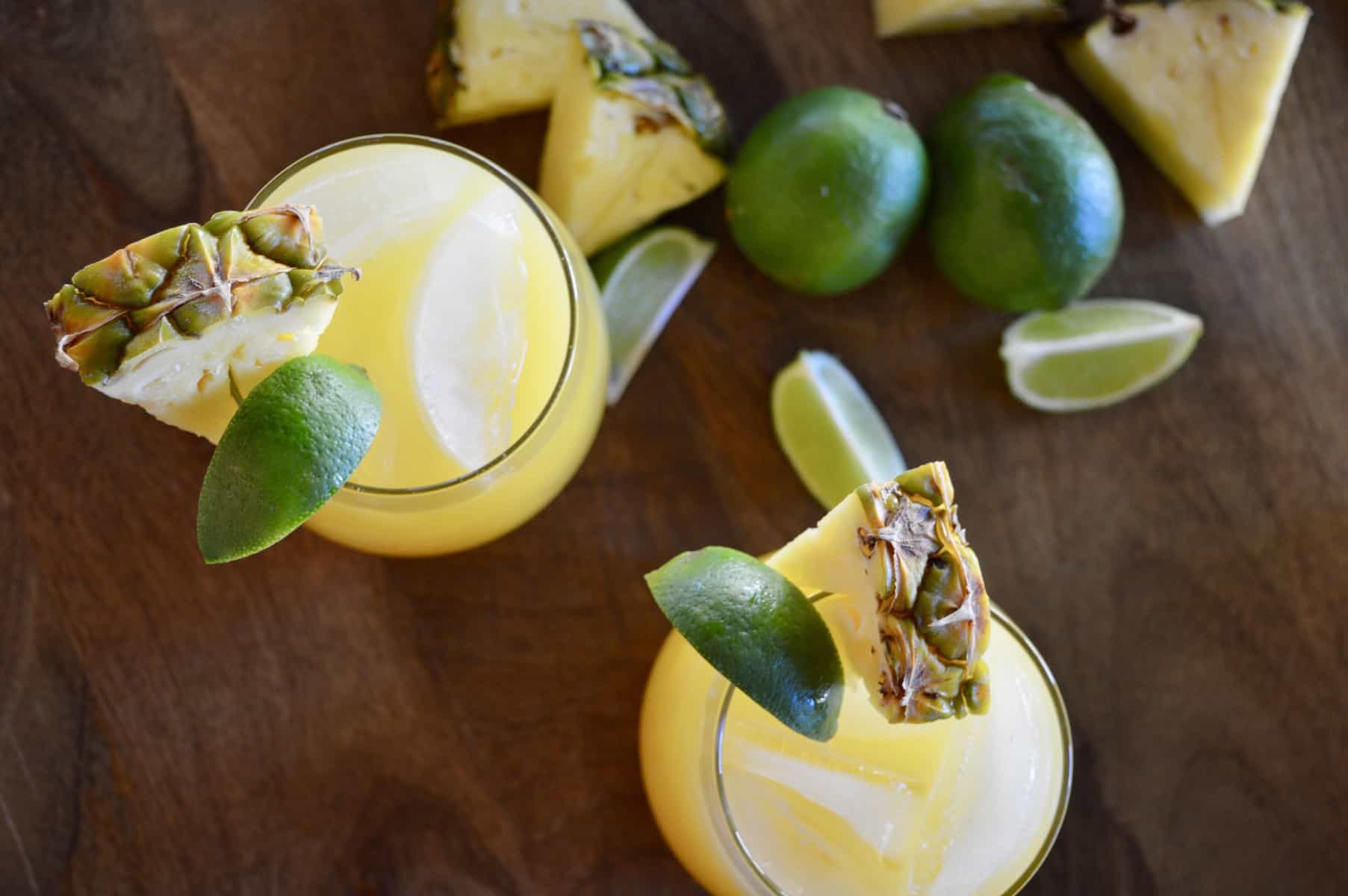 aerial view of pineapple margarita cocktails with lime wedges. 