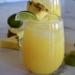 Glass of pineapple margarita with a lime and pineapple garnish.