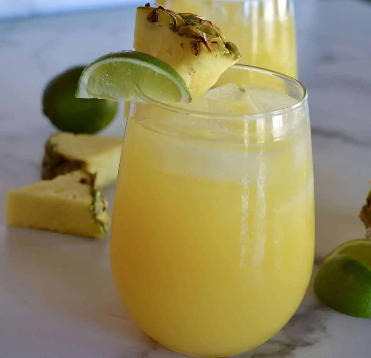 Glass of pineapple margarita with a lime and pineapple garnish. 