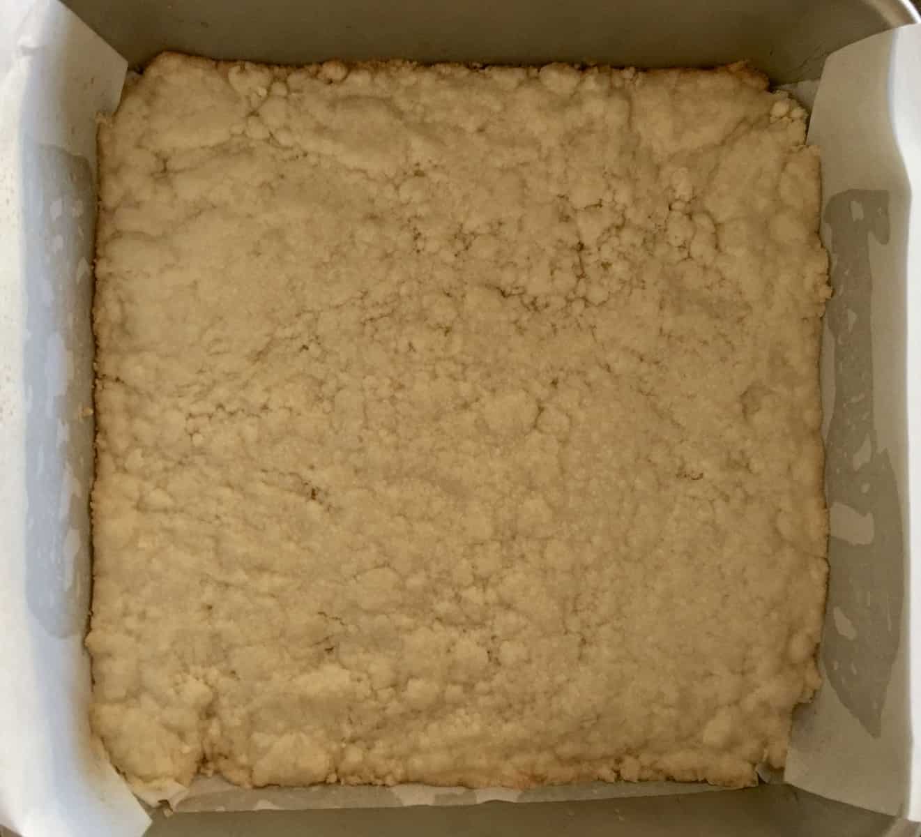 Shortbread pressed into the bottom of a greased and lined baking pan.