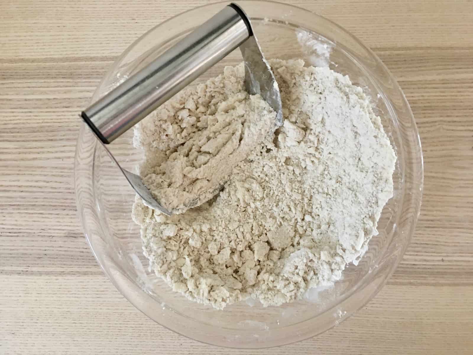 shortbread mixture in a glass bowl with a pastry cutter.