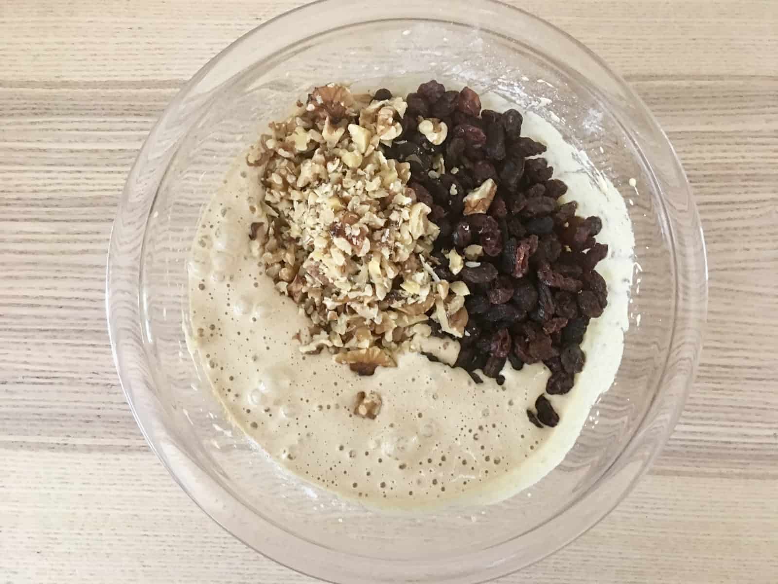 Glass bowl with egg brown sugar mixture, and walnuts and raisins on top. 