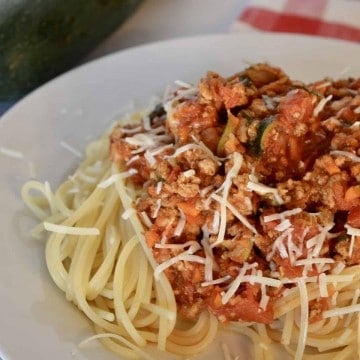 Turkey Vegetable Spaghetti on a white plate with zucchini in the background.