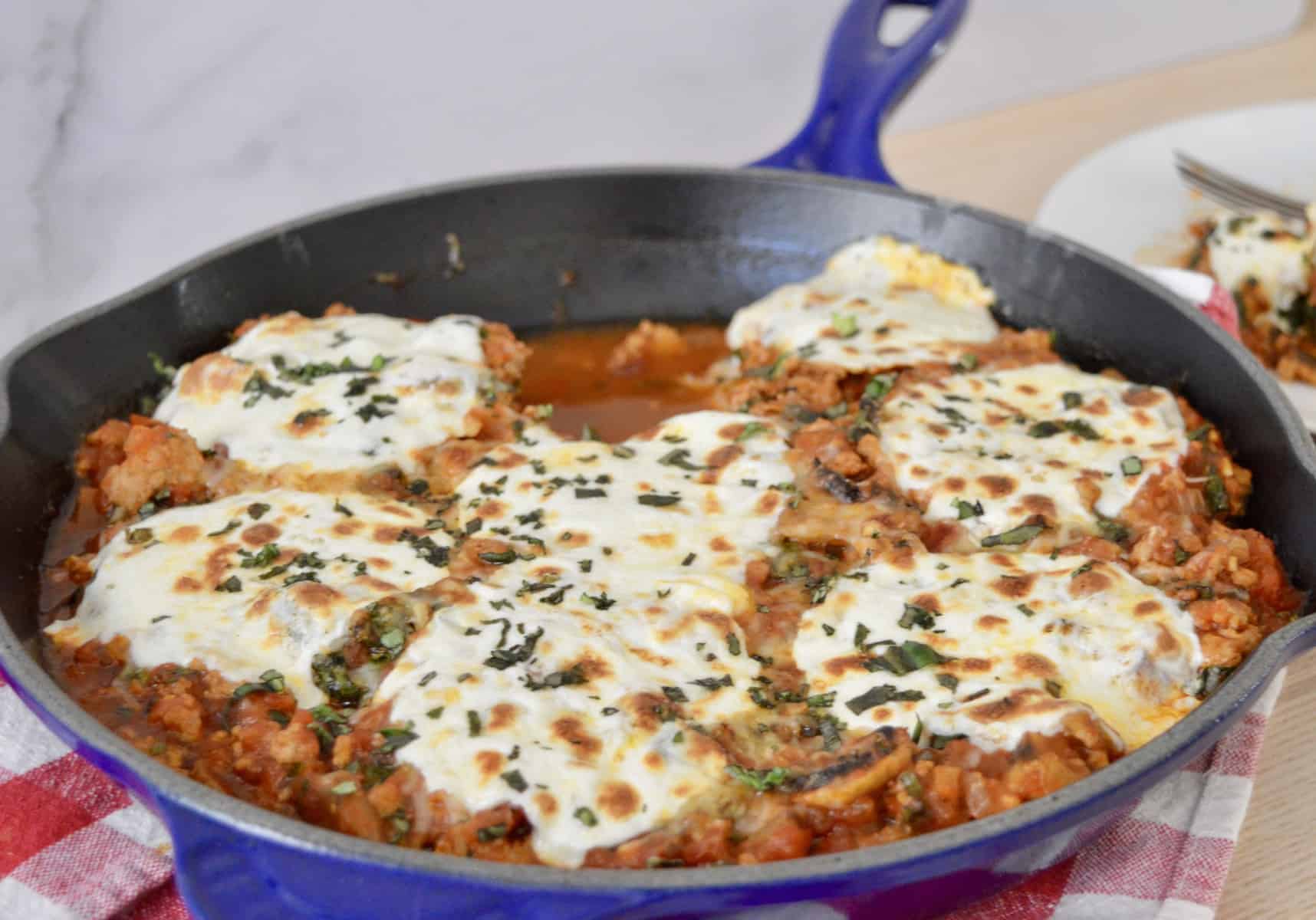 cast iron pan with sauce and cheese on top. 