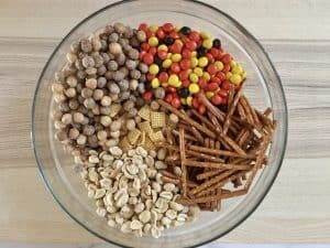 peanuts, Chex cereal, pretzels, and Reese's pieces in a large glass bowl.