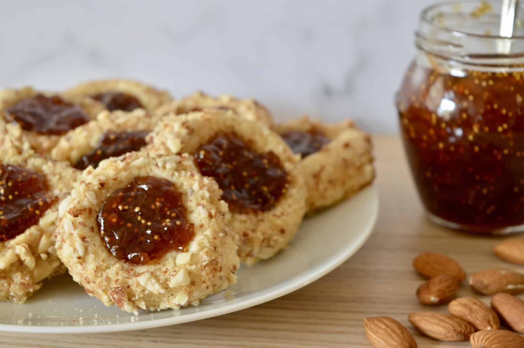 Italian Fig and almond cookies on a plate with fig jam in the background. 