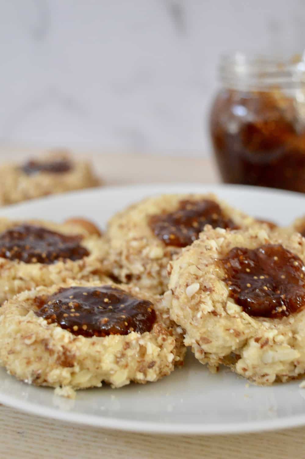 Italian Fig and Almond Thumbprint Cookies on a white plate with fig spread in the background.