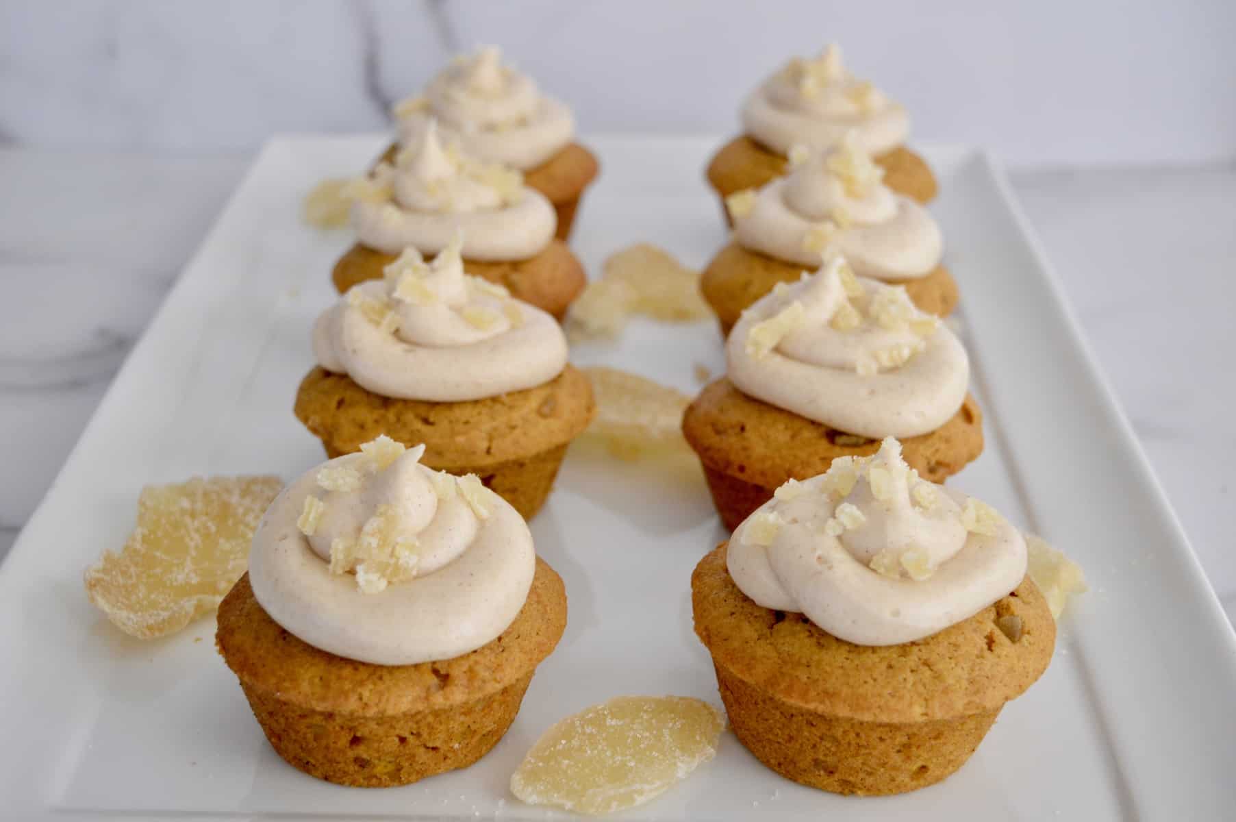 pumpkin ginger cupcakes lined up on a white serving platter.