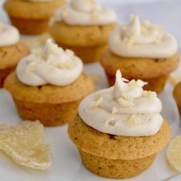 pumpkin ginger cupcakes with cream cheese frosting on a white platter with candied ginger.