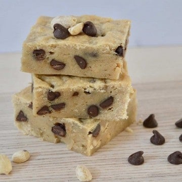 Peanut Butter Banana Blondies with chocolate chips stacked on a wood surface.