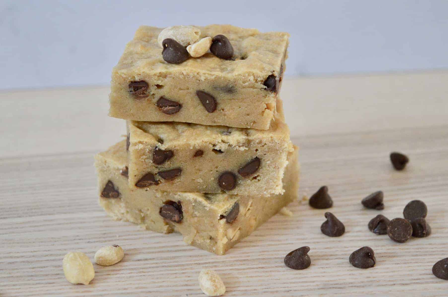 Peanut Butter Banana Blondies with chocolate chips stacked on a wood surface. 