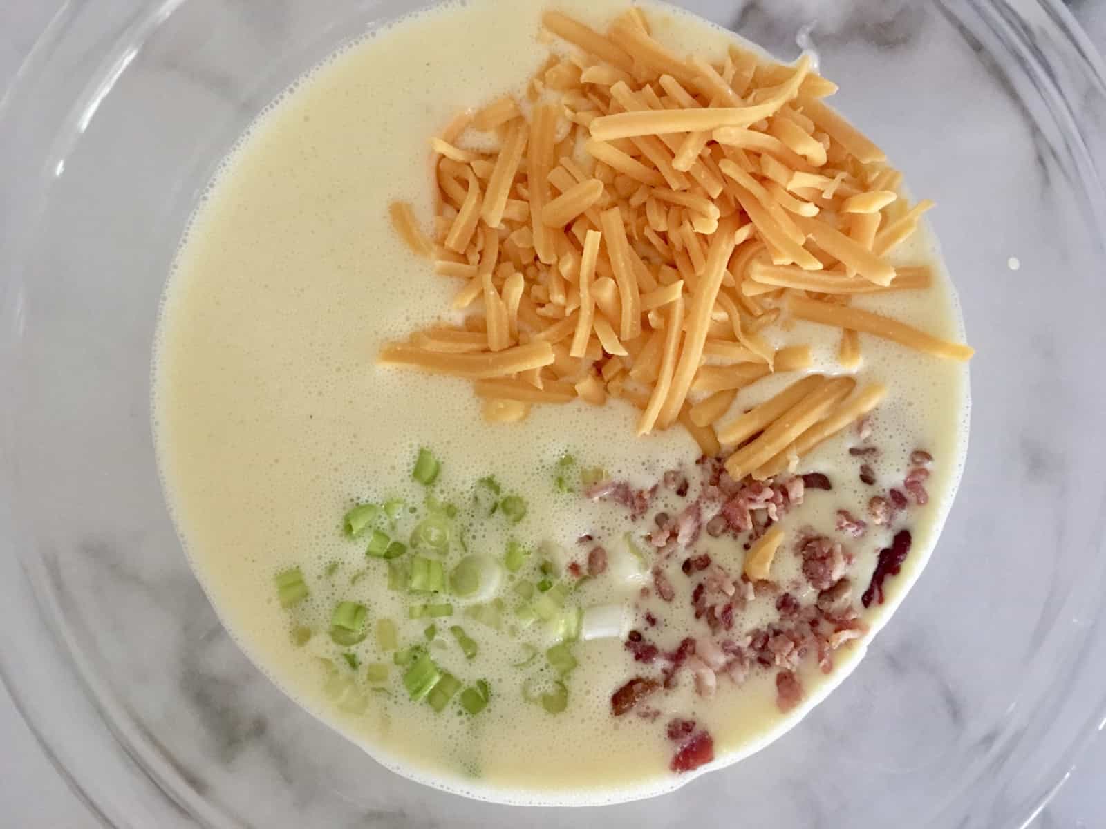 egg mixture in pie dish with mixings and green onions on top. 