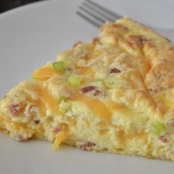 slice of crustless quiche on a white plate with a fork.