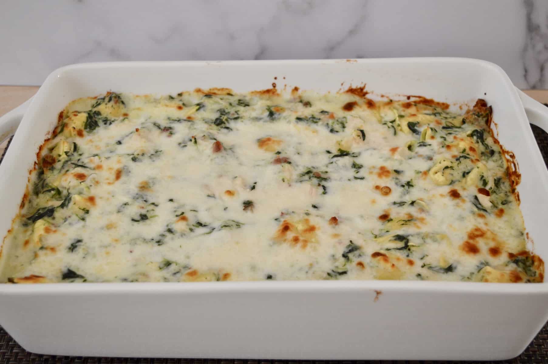 white baking pan with chicken bacon spinach tortellini inside. 