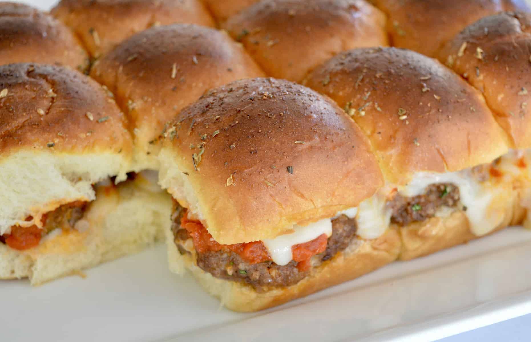 mini baked meatball sandwiches on a white serving platter. 