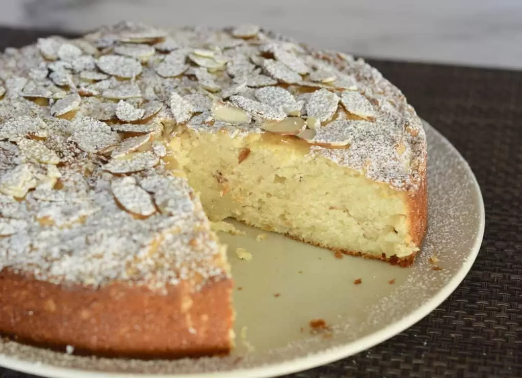 Almond Ricotta cake with slice almonds and powdered sugar on top.