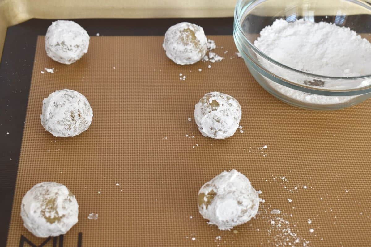 balls of dough tossed in powdered sugar on a baking sheet. 