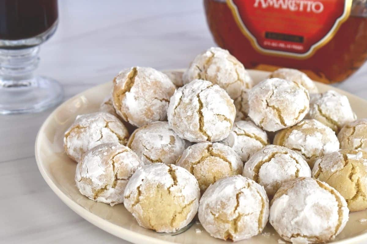 Amaretti Biscuits on a white plate with amaretto in the background. 