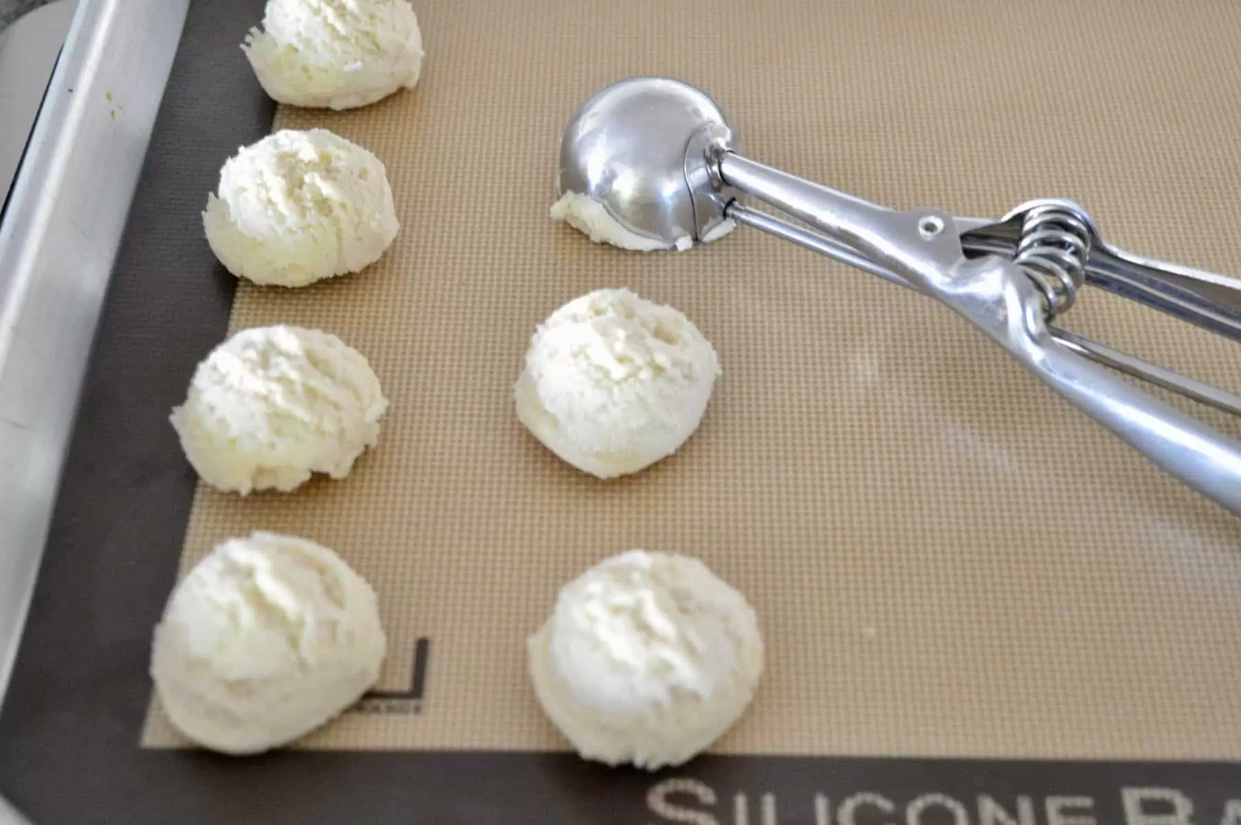 cookie scoop portioning dough on to baking mat.