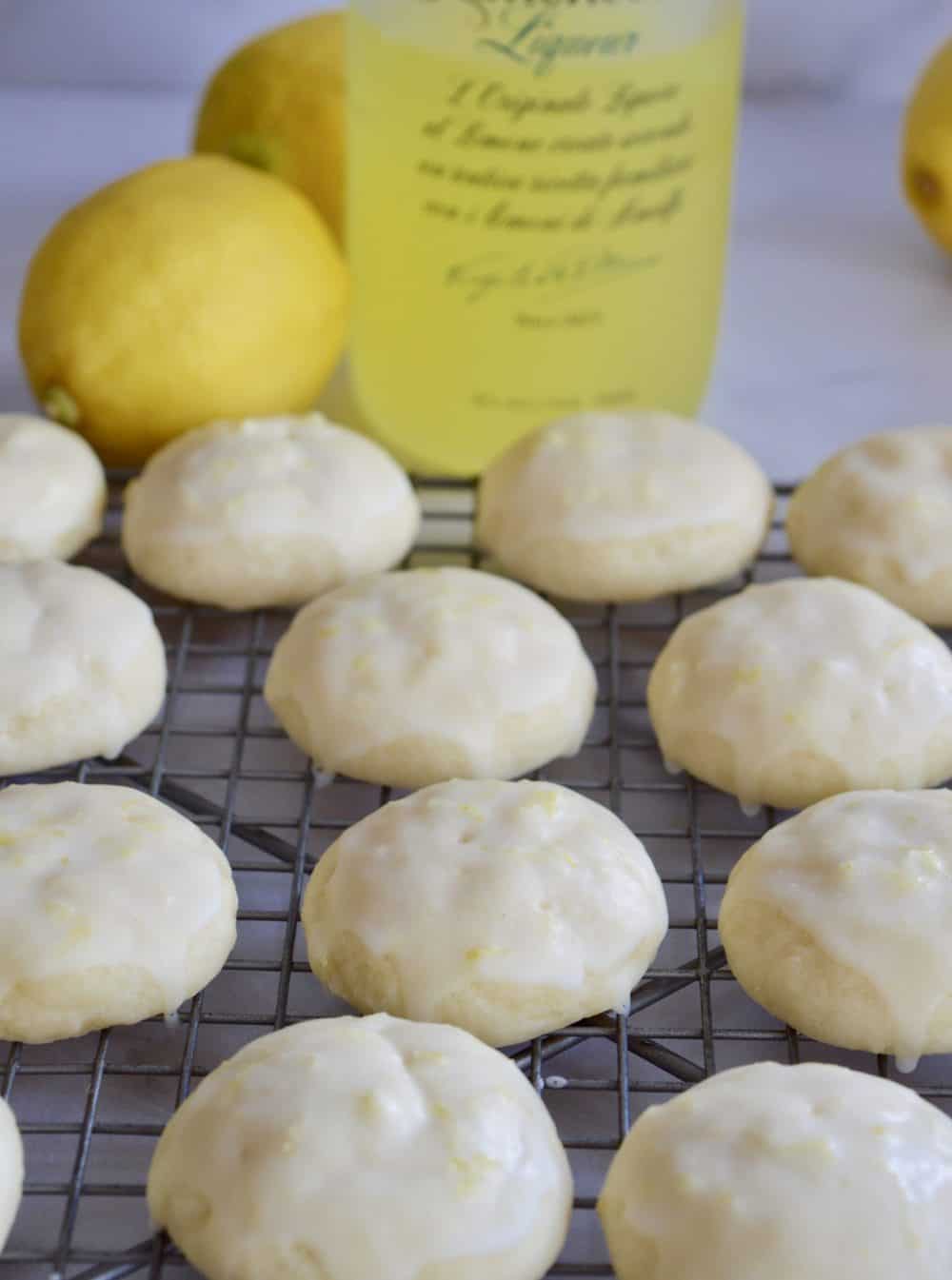 Limoncello Ricotta Cookies on a wire baking rack with limoncello liqueur in the background.