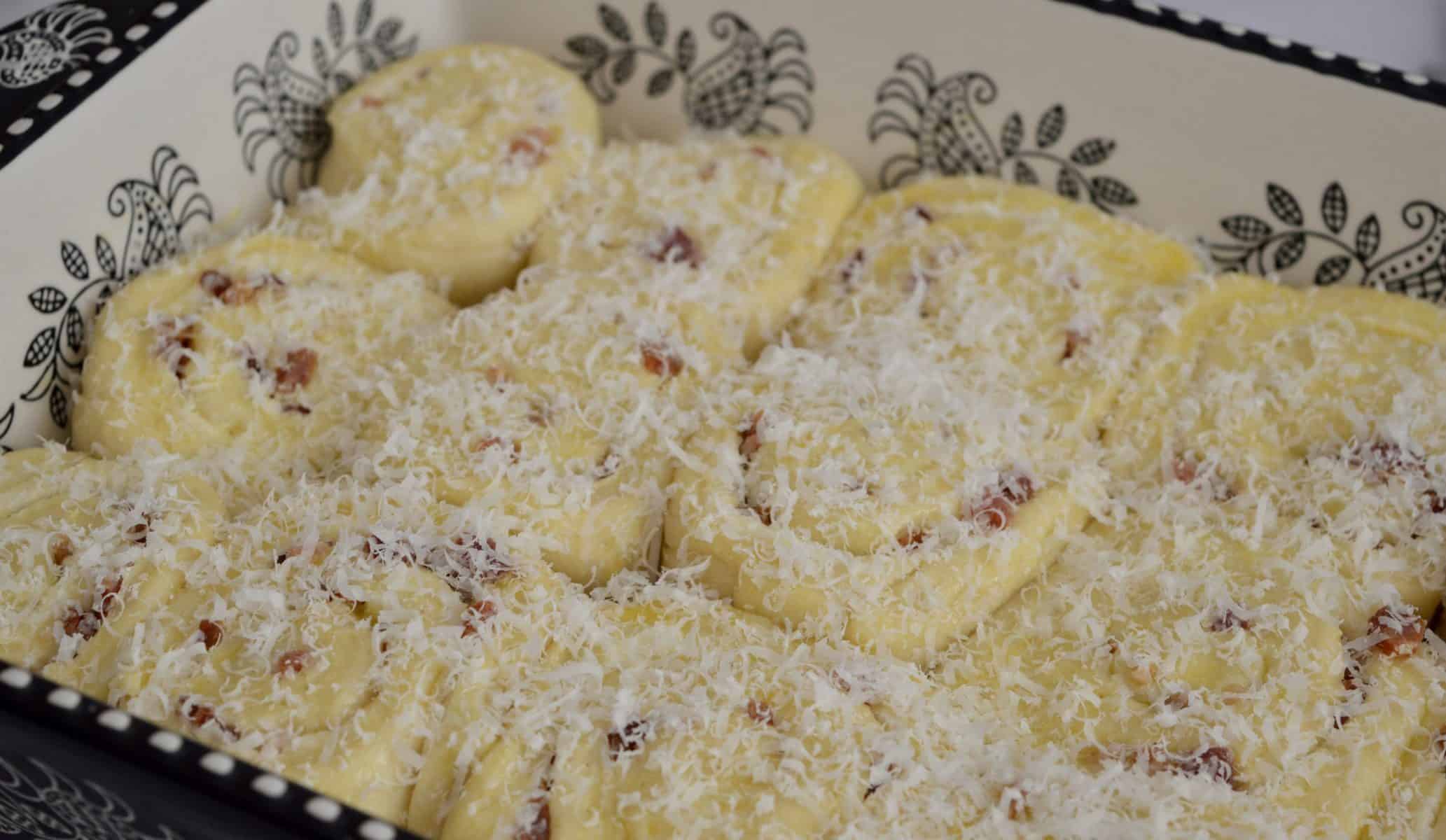 sprinkle the pinwheel bread rolls with shredded parmesan cheese.