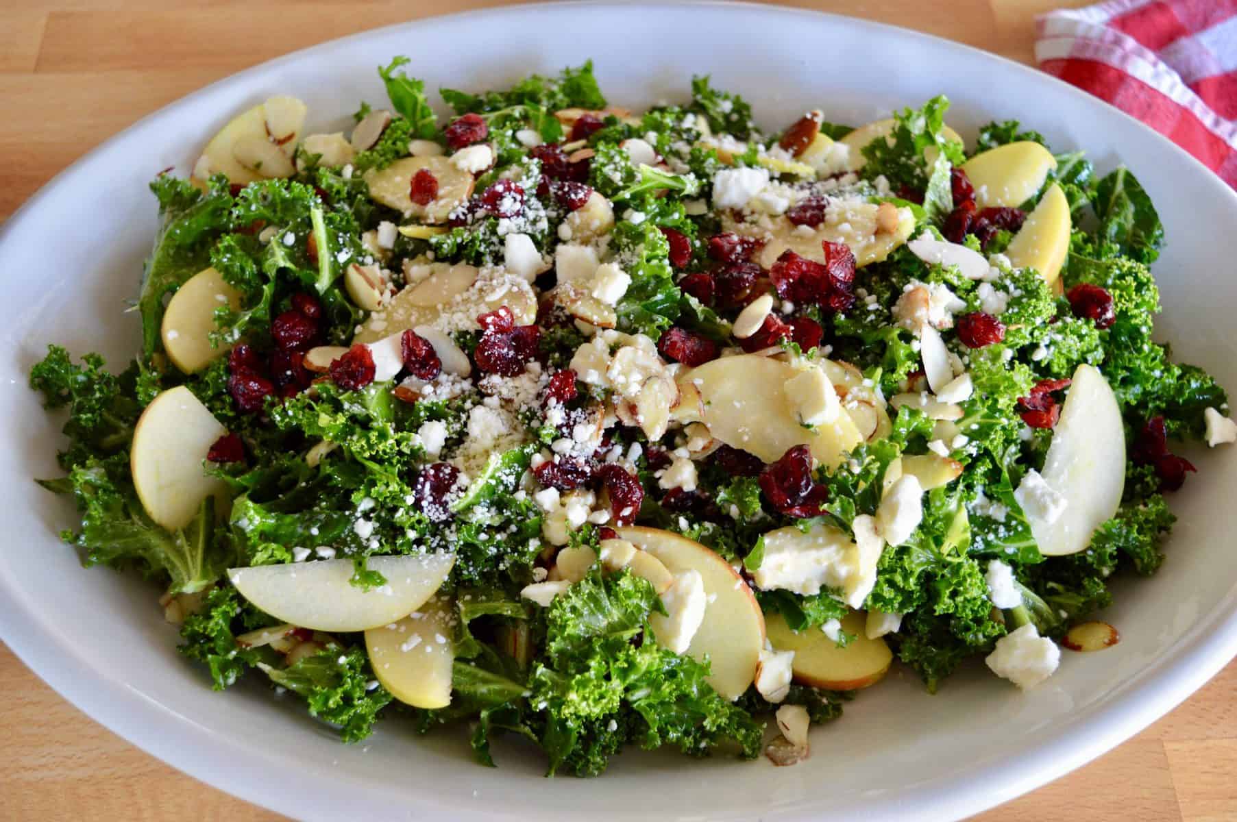 Overhead photo of kale cranberry feta salad in a white oval platter. 
