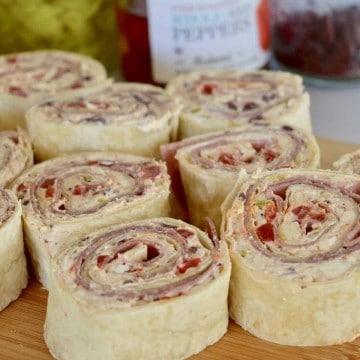 Italian antipasto pinwheels on a wooden cutting board.