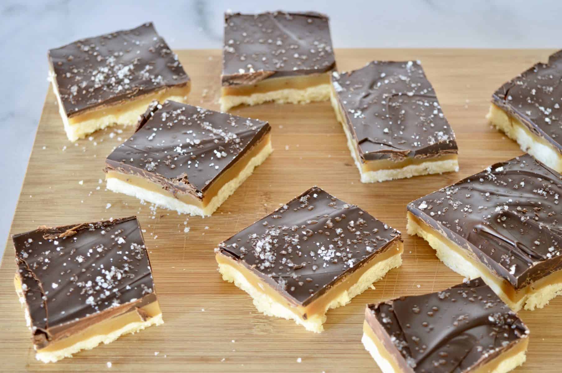 Salted Chocolate Caramel Squares on a wood cutting board. 