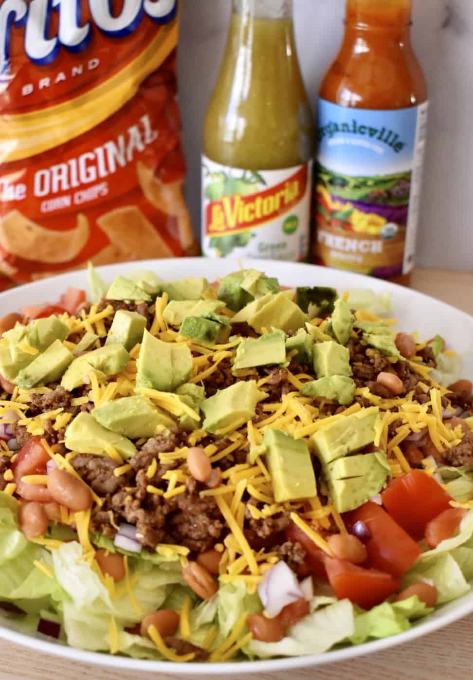 Chips and dressing located behind a picture of the salad. 