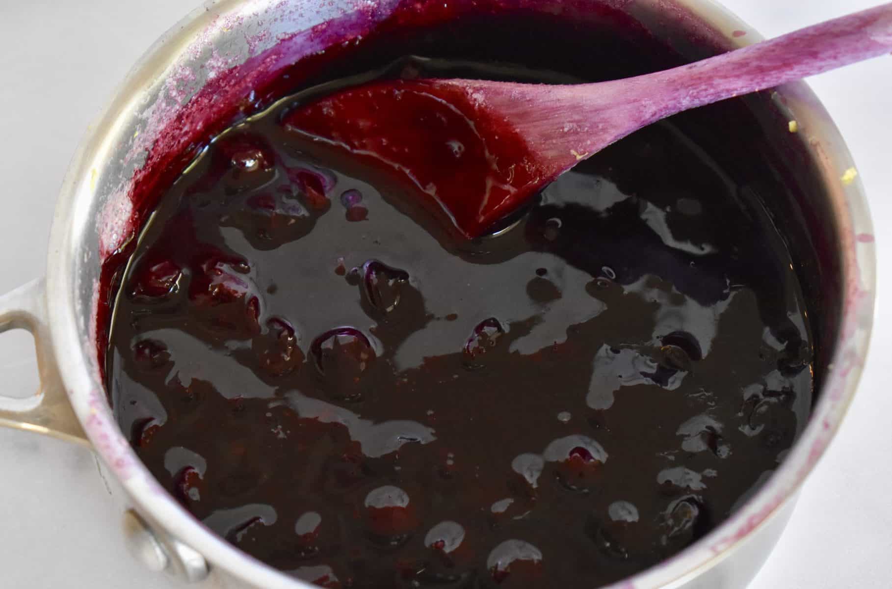 Saucepan with blueberry sauce in it. 