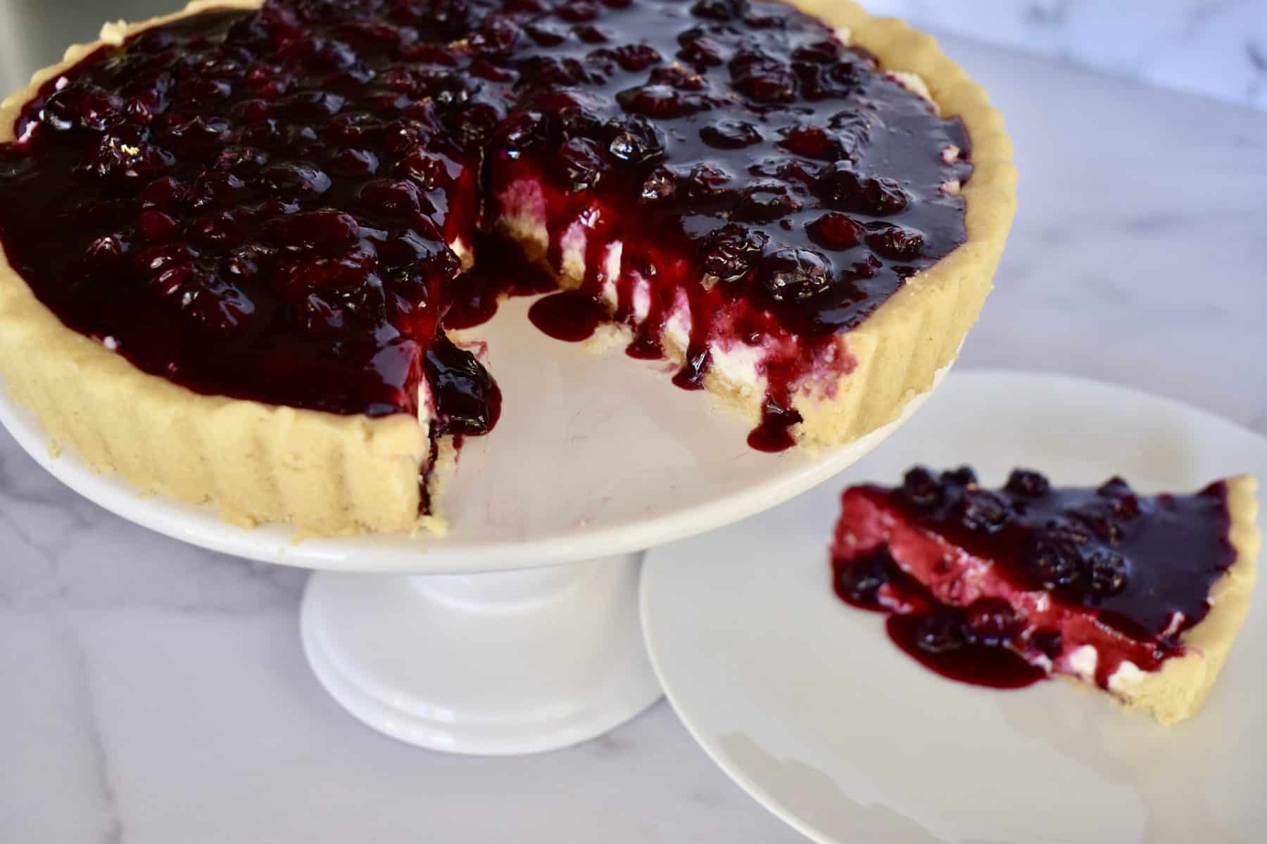 Blueberry Lemon Mascarpone Tart on a white pedestal.