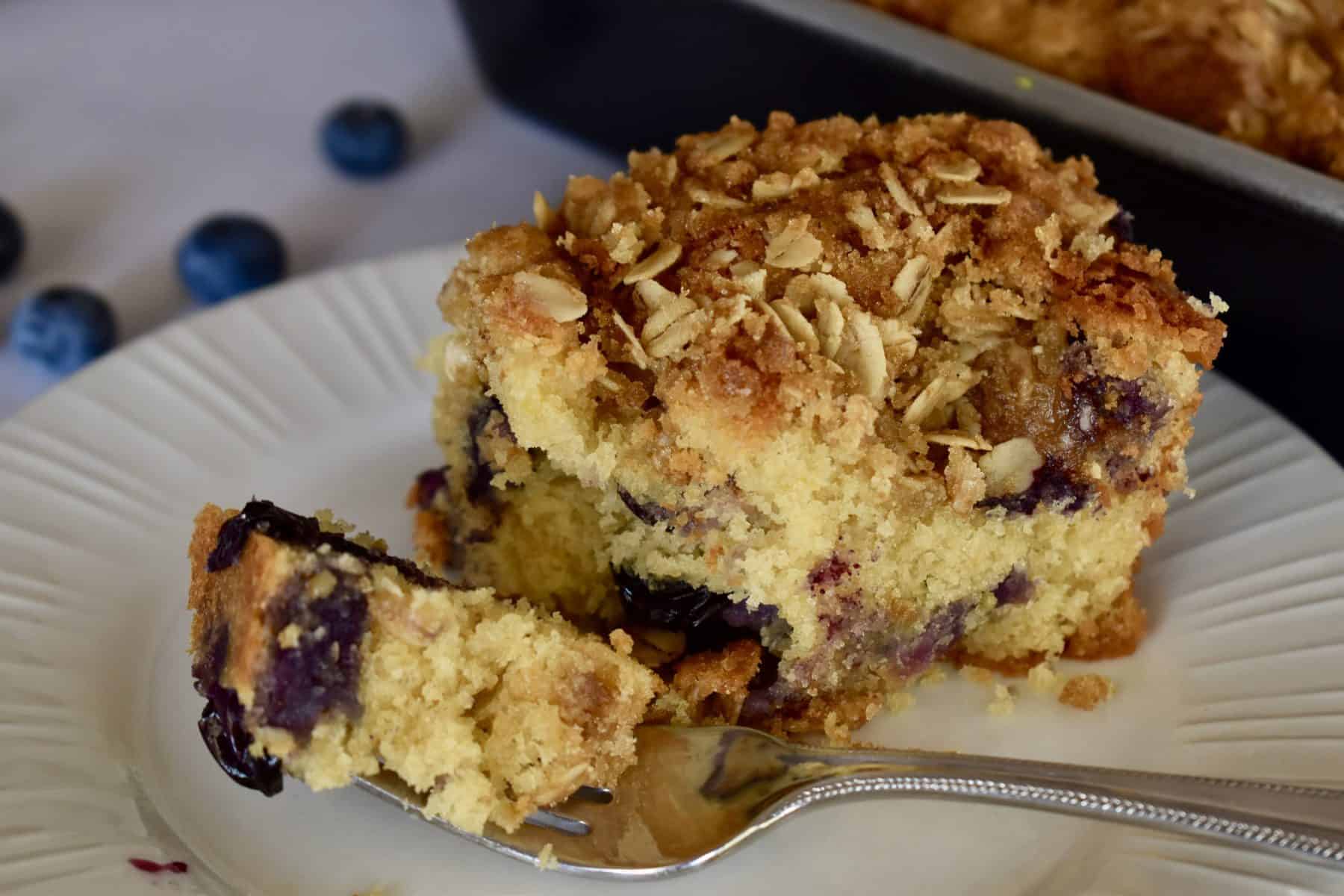 Blueberry Ricotta Coffee Cake on a white plate with a fork.