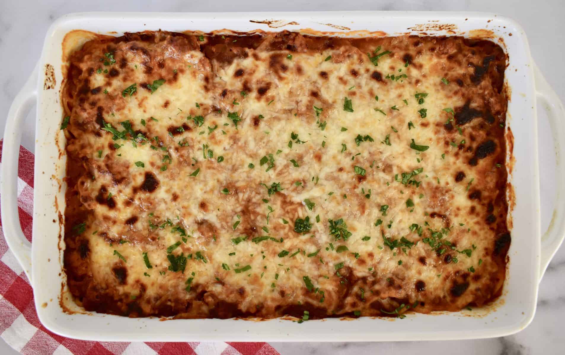 Baked spaghetti with ground turkey in a white casserole dish. 