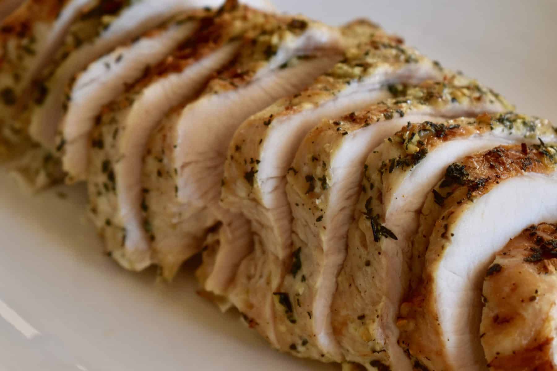 Slow cooker turkey breast cut into slices on a white plate. 