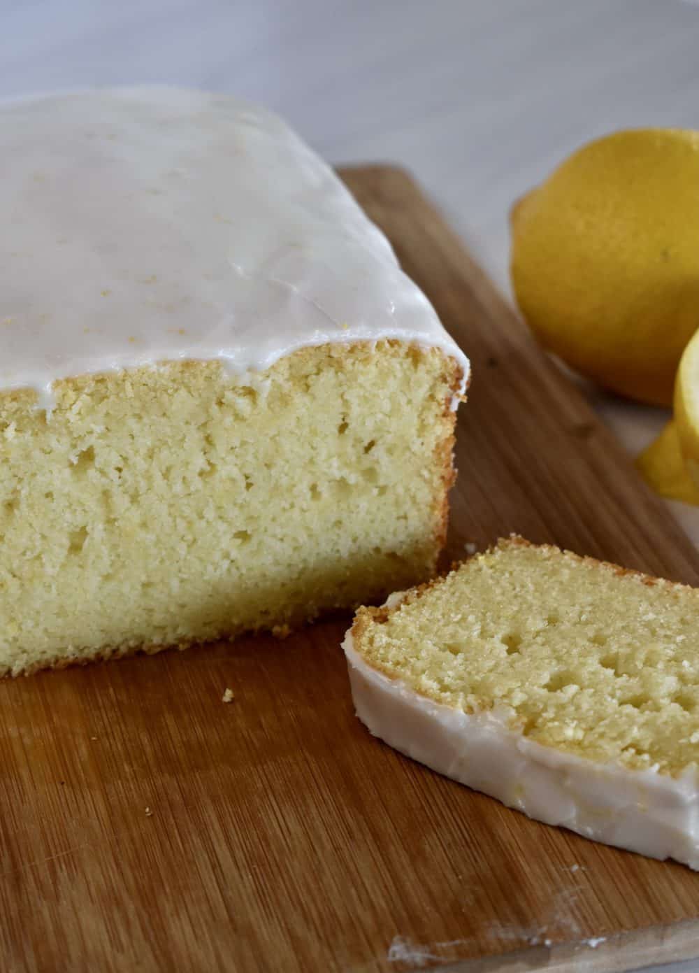 Lemon Ricotta Pound Cake on a wood cutting board with a lemon in the background.