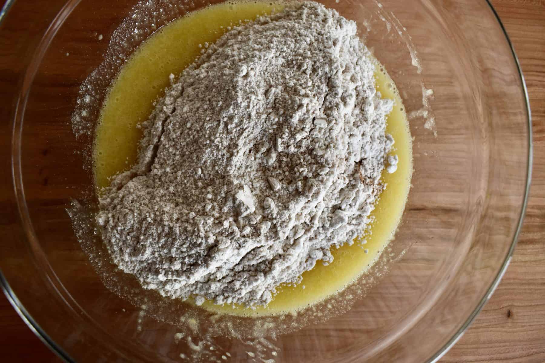 dry ingredients poured on top of the wet ingredients in a glass bowl. 