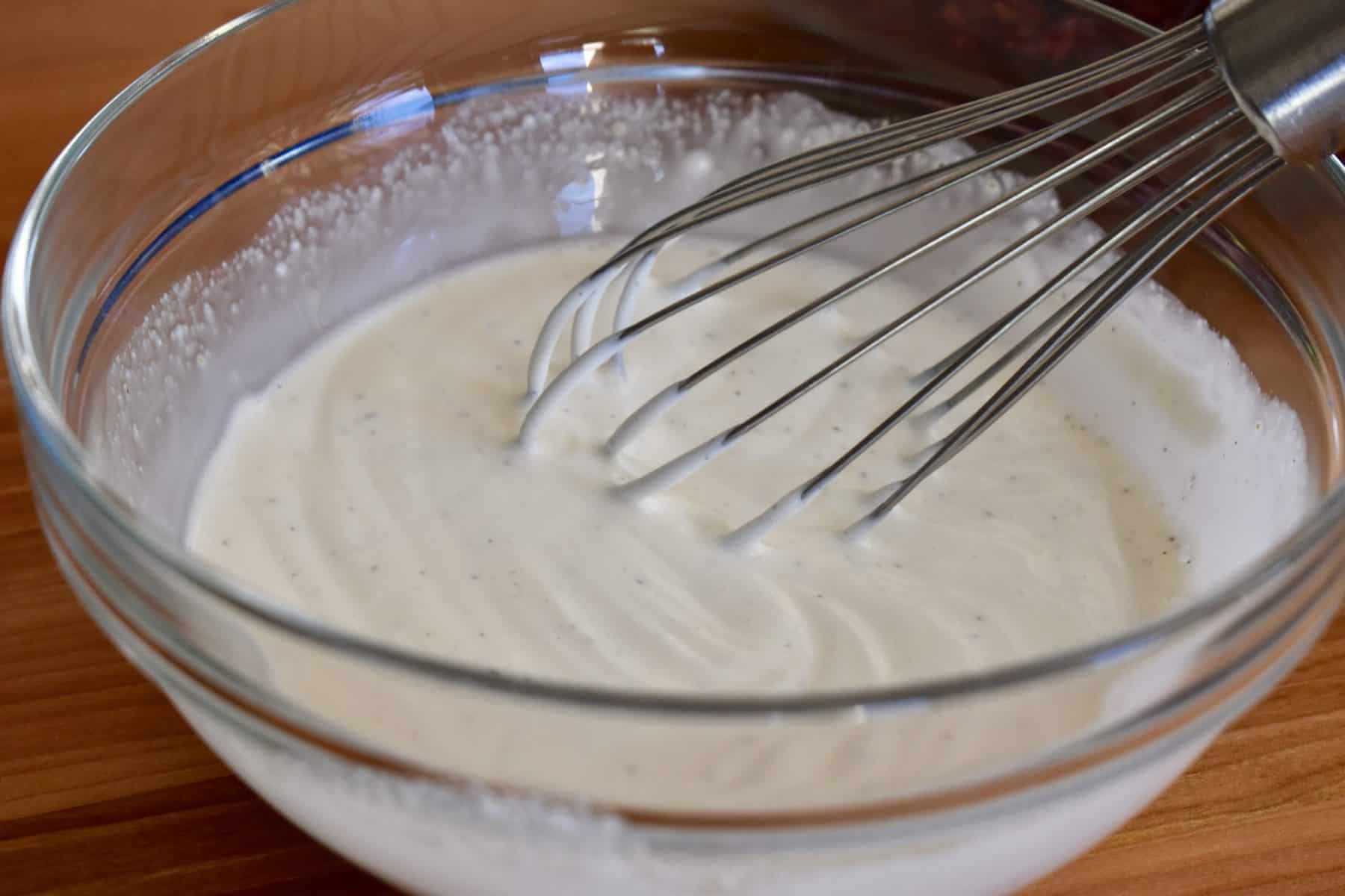 Greek Yogurt dressing in a bowl with a whisk. 