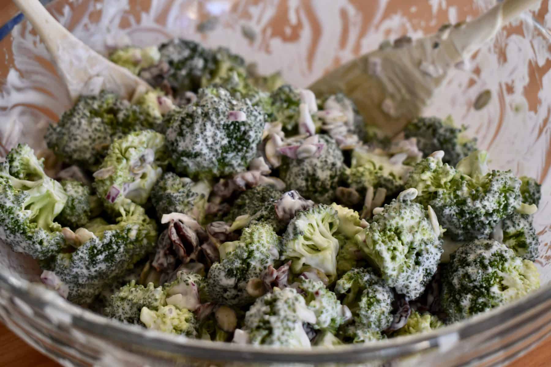 tossed broccoli cranberry salad with greek yogurt dressing in a glass bowl. 