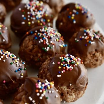 Crispy Nutella Truffles with chocolate and sprinkles on top on a white plate.