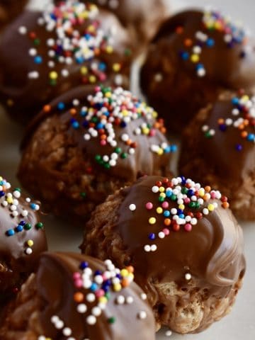 Crispy Nutella Truffles with chocolate and sprinkles on top on a white plate.