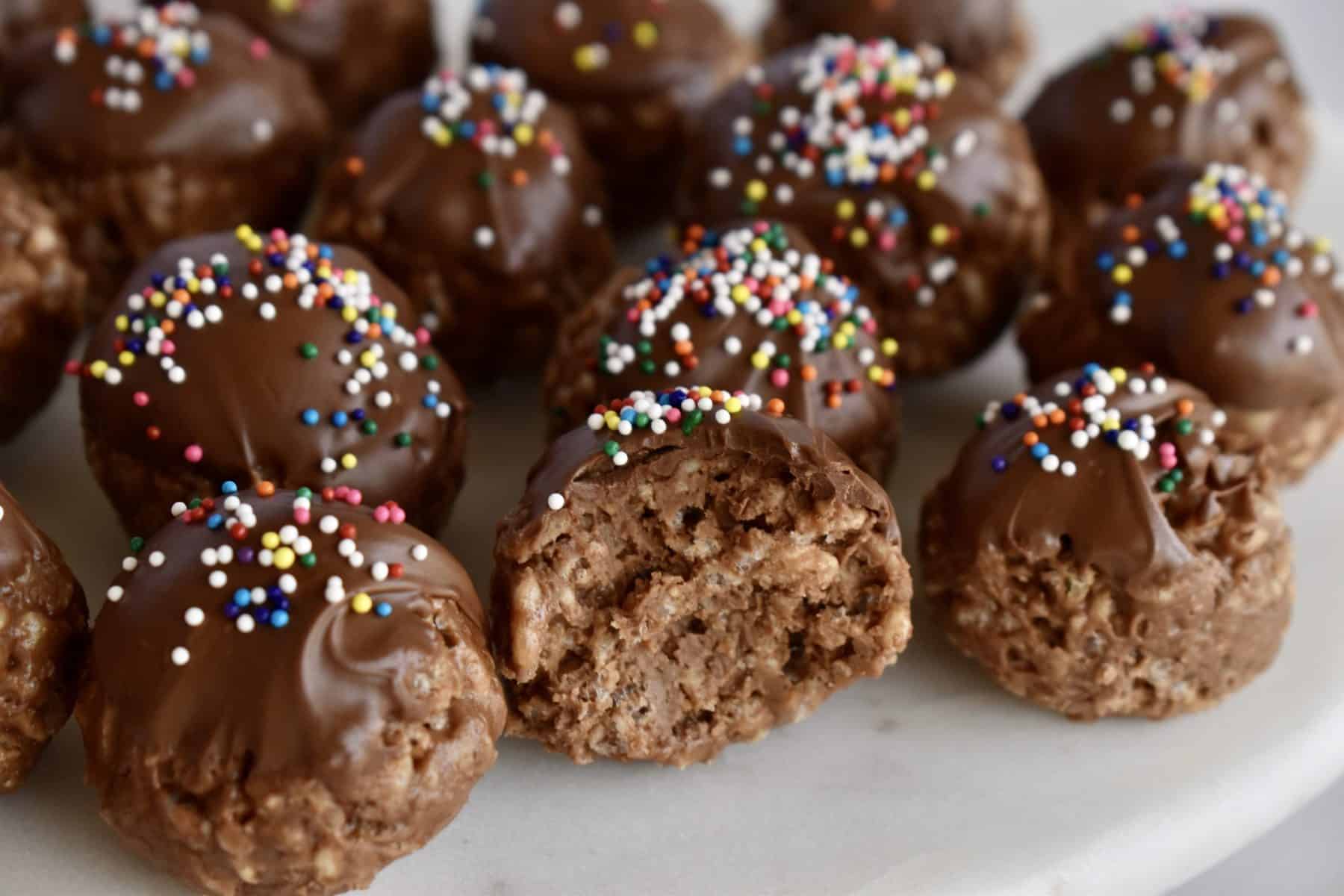 Crispy Nutella Truffles on a white plate with a bite taken out of one of them. 